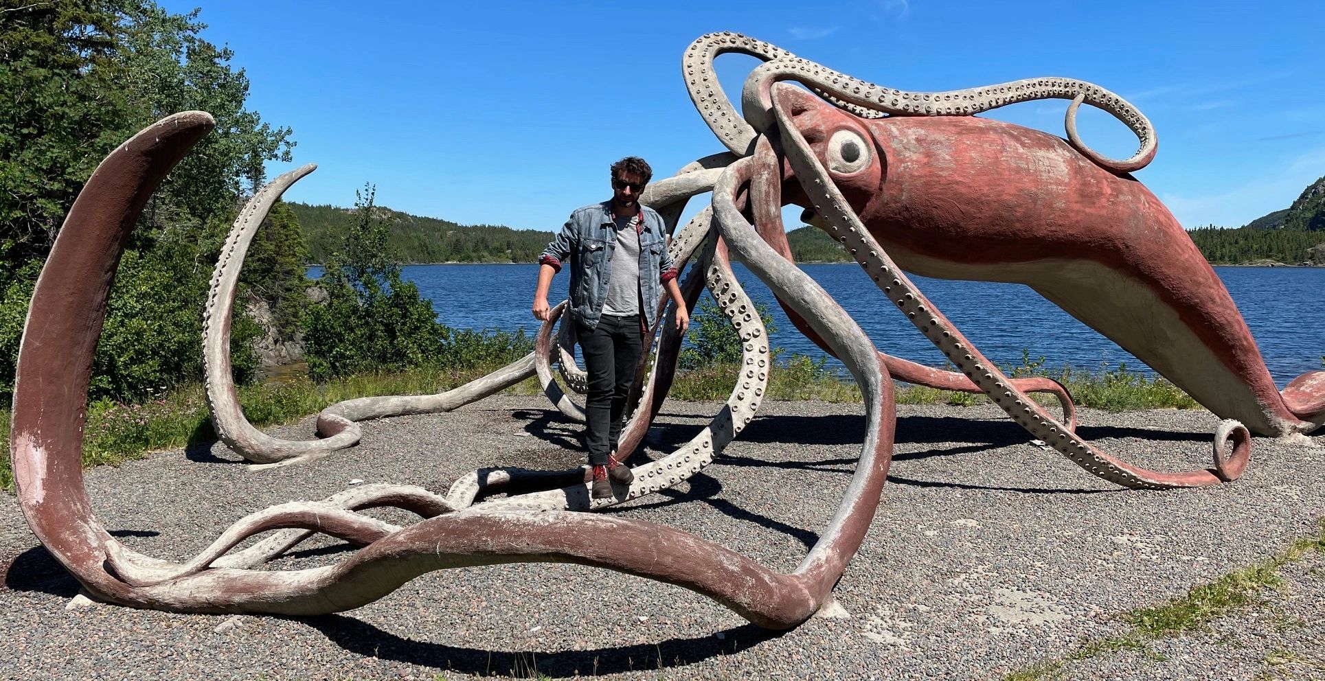 Backyard History's author Andrew MacLean with a life sized statue of a giant squid in Thimble Tickle, Newfoundland.