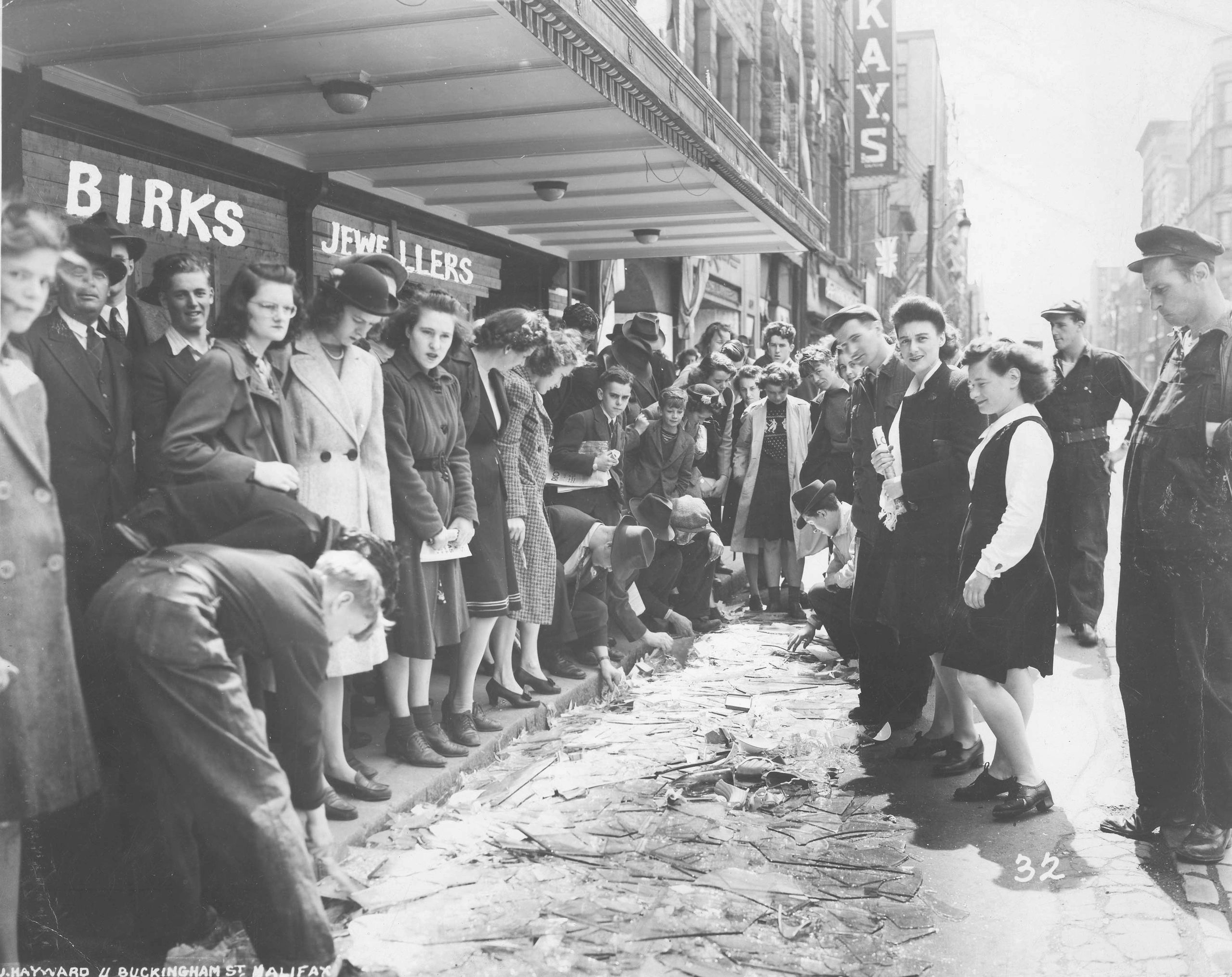 Haligonians standing on Barrington Street look at the broken glass from destroyed windows after the second Halifax Explosion in 1945.